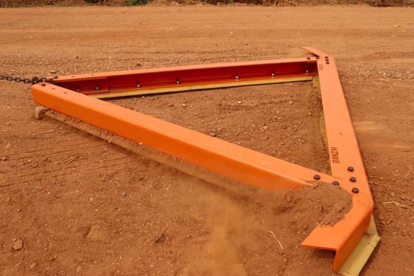 Equipamento Banzai nivelando o solo de uma estrada rural